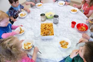 A group of children eating pasta