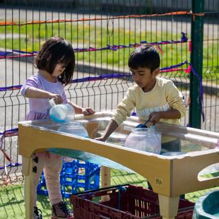 A couple of children playing with water outdoors.