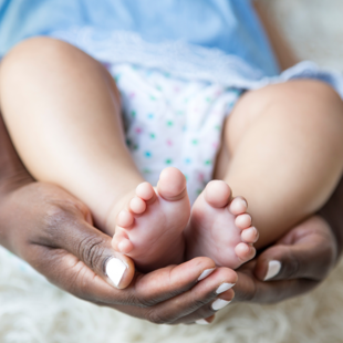 feet of newborn baby being held in adult hands