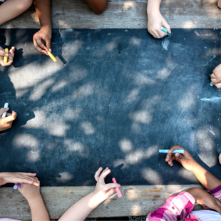 children drawing on a chalkboard outdoors