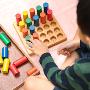 child arranging colourful wooden sensorial blocks