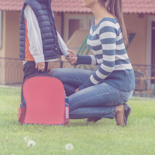 person kneeling in front of child outside of school setting