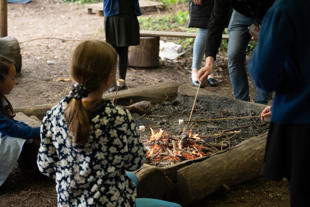 A group of people around a fire pit toasting marshmallows
