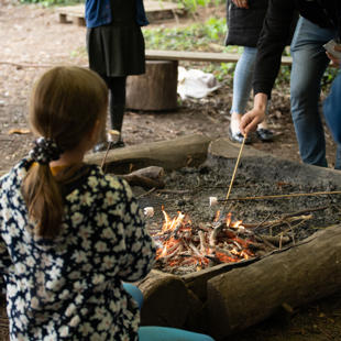 A group of people around a fire pit toasting marshmallows