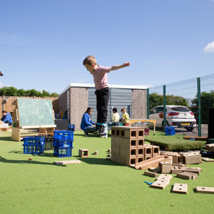 A child jumping of wooden blocks outdoors