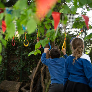 Three children holding objects from a tree