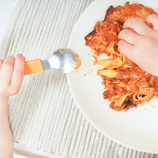 young child eating lasagne