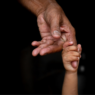 an elderly hand gently holding a baby's hand against a black background