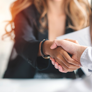 two business professionals shaking hands over a document