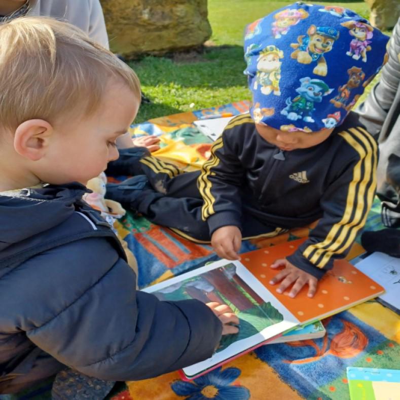 Two young children reading outdoors