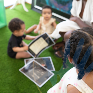 group of babies and young children exploring learning materials with an adult