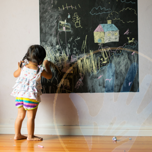 baby pupil draws with chalk on a blackboard