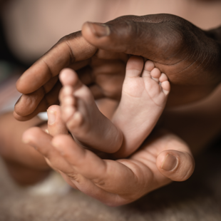 baby feet being held by two pairs of hands